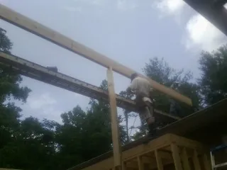 Carpenter setting a ridge beam over a new addition frame — Ice Dam Removal by Roofing Brothers in Caroleen