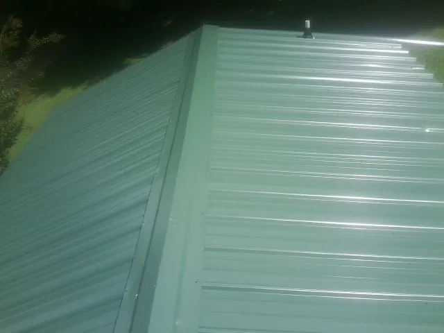 New green metal panels meeting at the ridge of a roof — Flat Roof Repair work by our crew in Caroleen