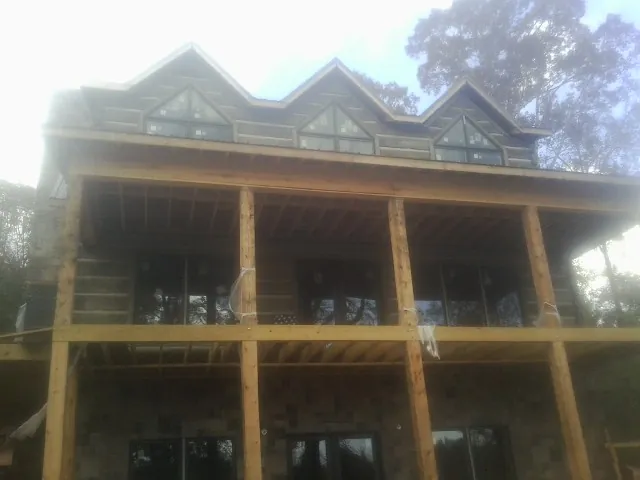 Dormers and porch framing on a large log home under construction — Roof Coating work by our crew in Caroleen