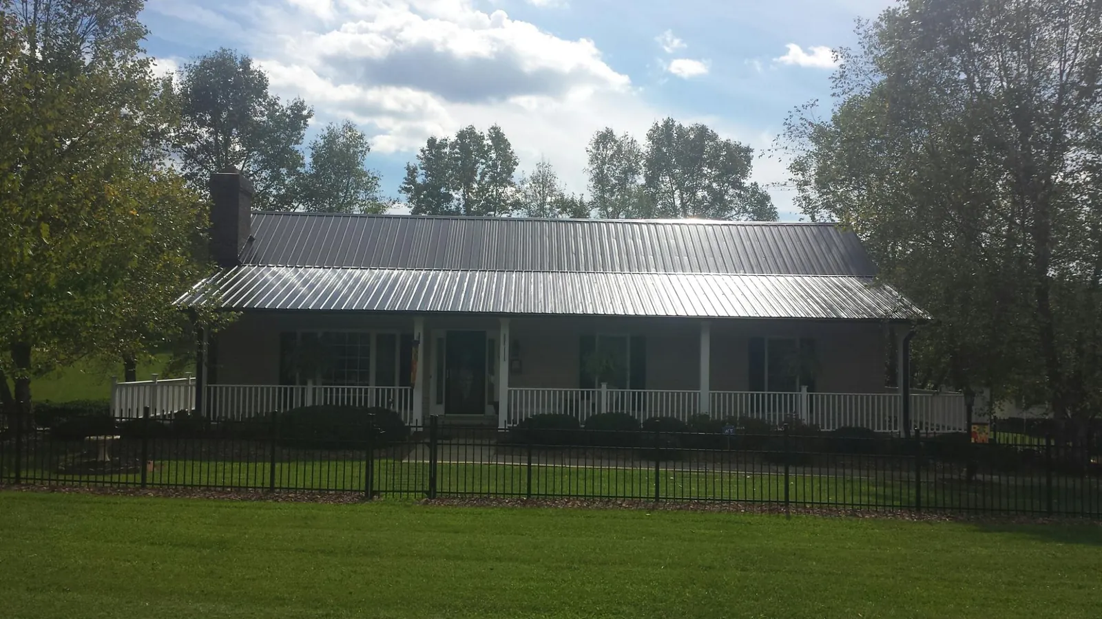 Gray metal roof on a brick ranch with a full width front porch — Gutter Guard Installation work by our crew in Caroleen