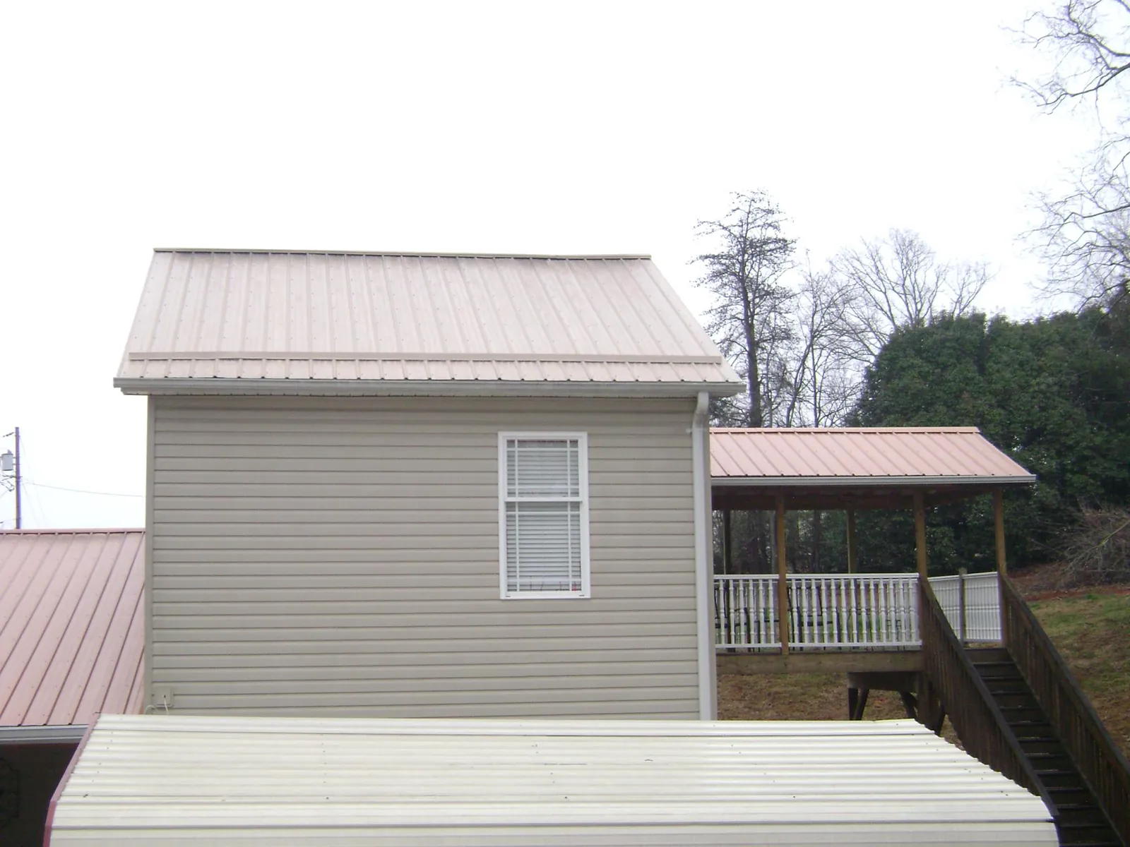 Tan metal roofs on a two story addition and attached porch, from a Roof Replacement job in Caroleen