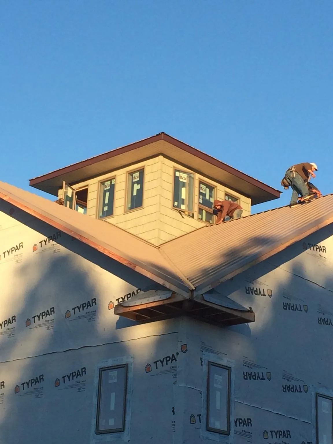 Roofers working around a rooftop cupola on a new metal roof at sunset — Roof Waterproofing in Caroleen by Roofing Brothers
